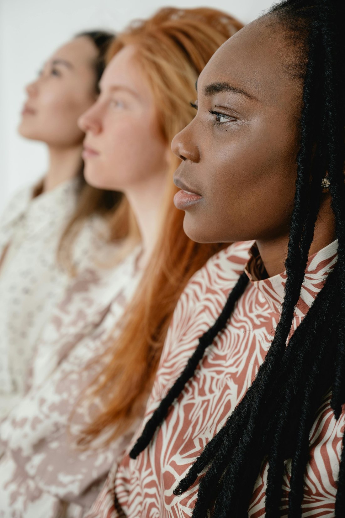 Three women standing together in profile.