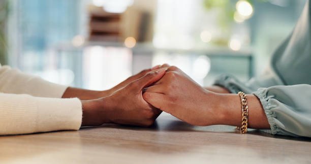 Two people holding hands across a table.