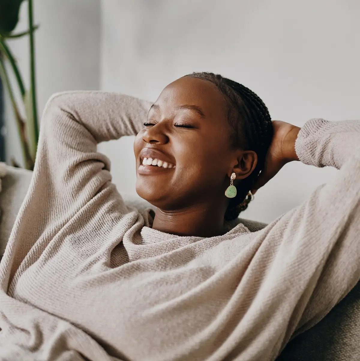 A woman resting on a sofa with her eyes closed, smiling.